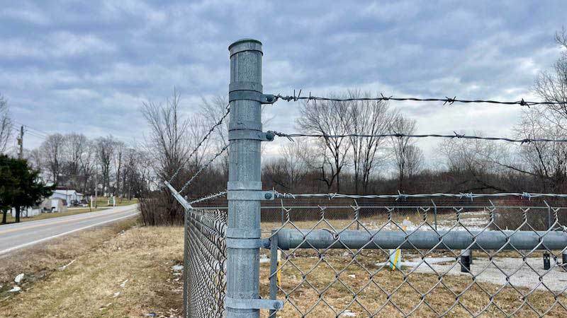 Chain link fence with barbed clearance wire